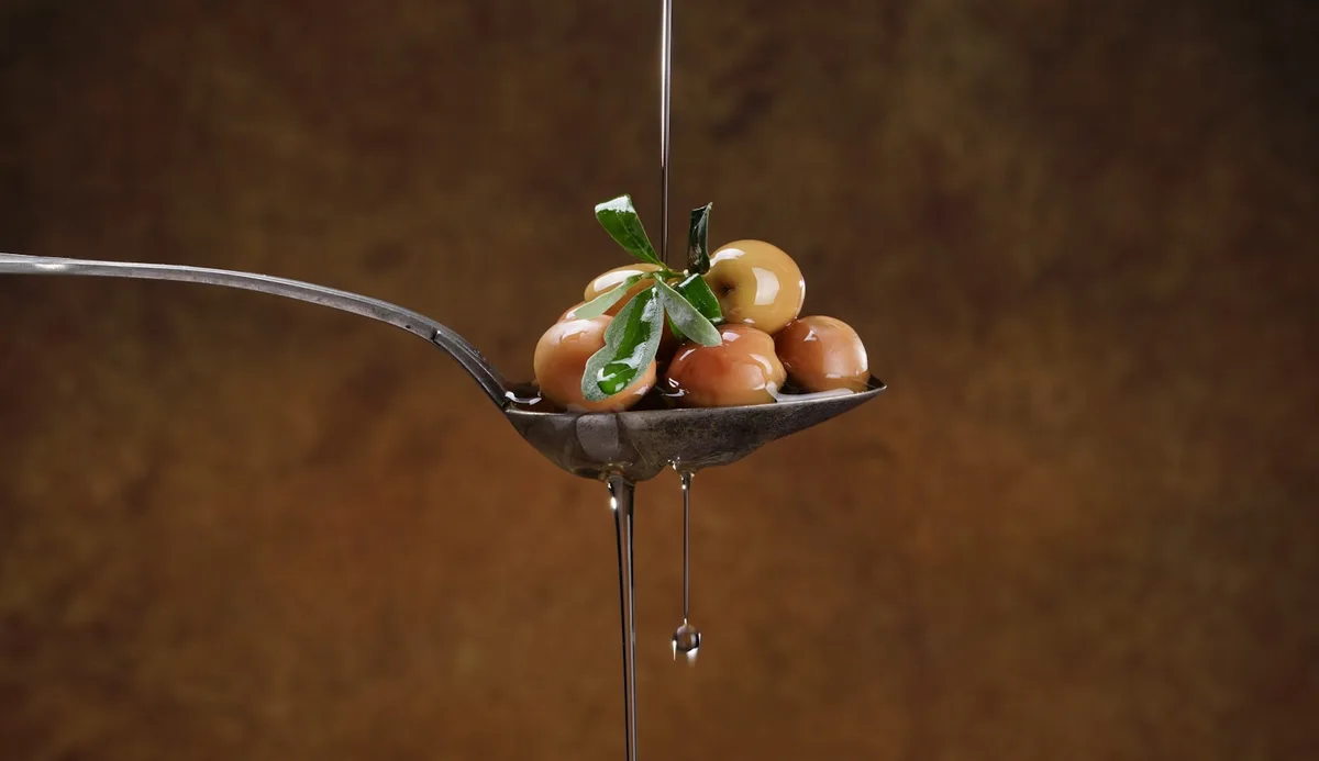 Spoon of olives with olive oil drizzle